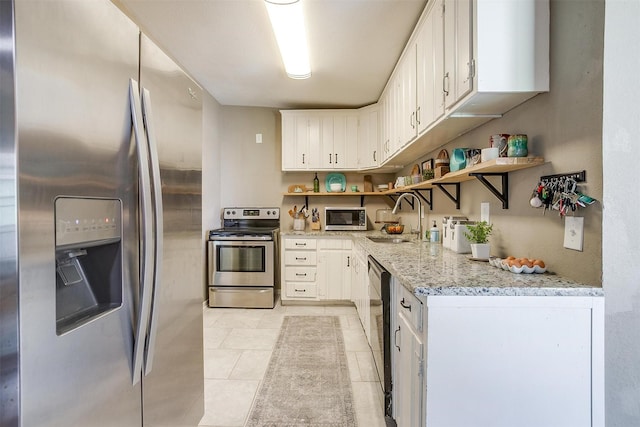 4913 Rutland Ave, Fort Worth, TX 76133 - kitchen featuring appliances with stainless steel finishes, open shelves, light tile patterned flooring, and white cabinetry