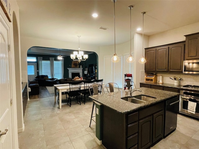 208 Mineral Point Dr, Aledo, TX 76008 - kitchen featuring appliances with stainless steel finishes, arched walkways, decorative backsplash, dark stone countertops, and a chandelier