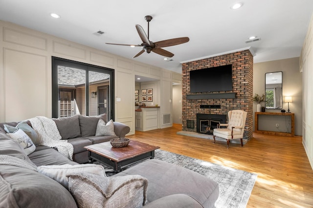 143 Shady Woods Ln, Denison, TX 75021 - living room with a ceiling fan, a brick fireplace, light wood-type flooring, a decorative wall, and recessed lighting