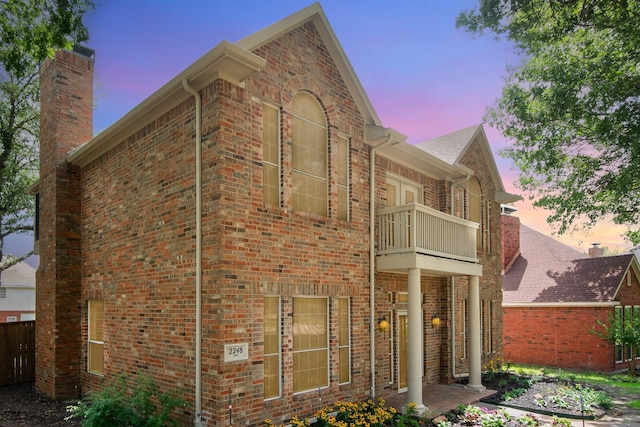 2248 Amy Ln, Plano, TX 75074 - property exterior at dusk with a balcony, brick siding, and a chimney