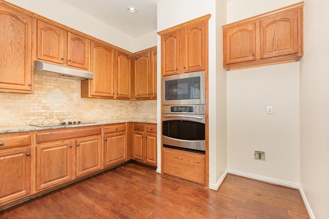 2248 Amy Ln, Plano, TX 75074 - kitchen featuring appliances with stainless steel finishes, under cabinet range hood, light stone countertops, backsplash, and dark wood-style flooring
