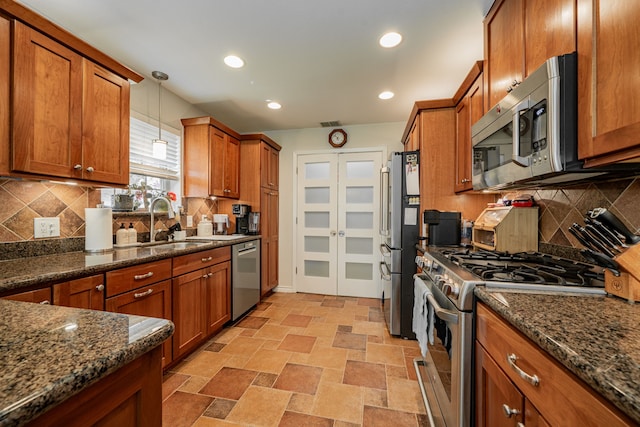 325 Los Santos Dr, Garland, TX 75043 - kitchen featuring stainless steel appliances, brown cabinets, decorative light fixtures, dark stone counters, and recessed lighting