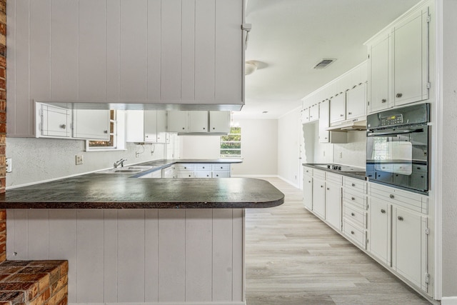 1016 Meadowlark Ln, Stephenville, TX 76401 - kitchen with black appliances, a peninsula, dark countertops, and light wood finished floors