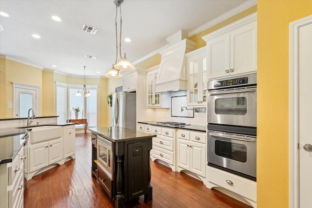 1313 Windstone Dr, Waco, TX 76712 - kitchen featuring stainless steel appliances, crown molding, dark wood-style flooring, glass insert cabinets, and a center island