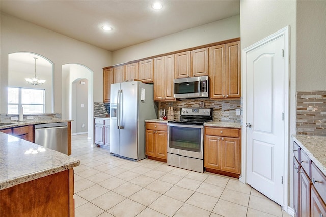 1201 Claire Ct, Burleson, TX 76028 - kitchen featuring appliances with stainless steel finishes, tasteful backsplash, arched walkways, a chandelier, and light tile patterned floors
