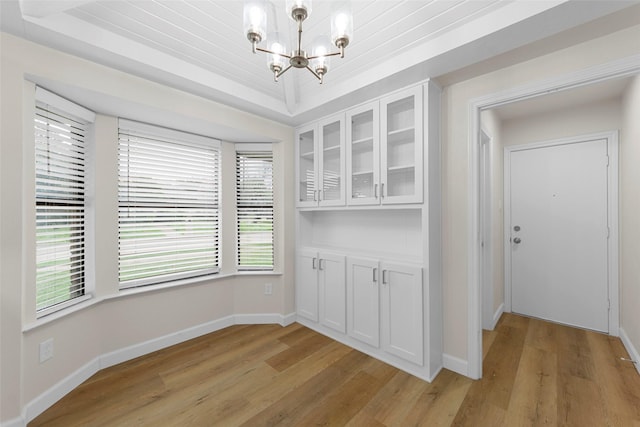 1721 Throwbridge Ln, Plano, TX 75023 - unfurnished dining area featuring a chandelier, light wood-style floors, and a tray ceiling