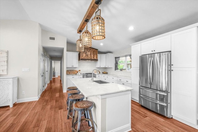 612 W Park Ave, Weatherford, TX 76086 - kitchen featuring freestanding refrigerator, vaulted ceiling, wood finished floors, light countertops, and white cabinets