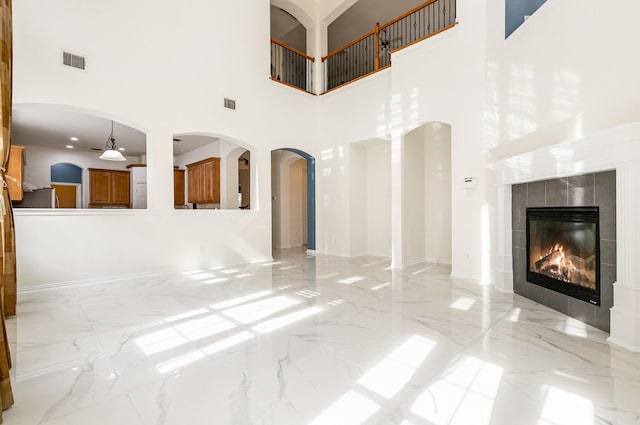2742 Hidden Knoll Trl, Frisco, TX 75034 - unfurnished living room with a towering ceiling, light marble finish floors, and a tile fireplace