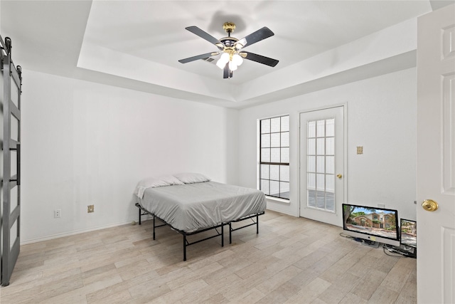 2707 Garden Springs Dr, Richardson, TX 75082 - bedroom featuring a barn door, a raised ceiling, light wood-style floors, and ceiling fan
