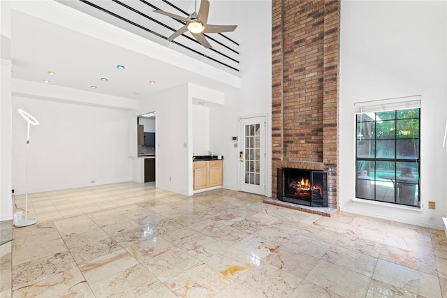 2707 Garden Springs Dr, Richardson, TX 75082 - unfurnished living room featuring a towering ceiling, light marble finish floors, ceiling fan, and a brick fireplace