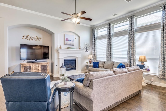 3300 Western Bluff Ct, Mansfield, TX 76063 - living area with ceiling fan, healthy amount of natural light, a glass covered fireplace, crown molding, and dark wood-style flooring