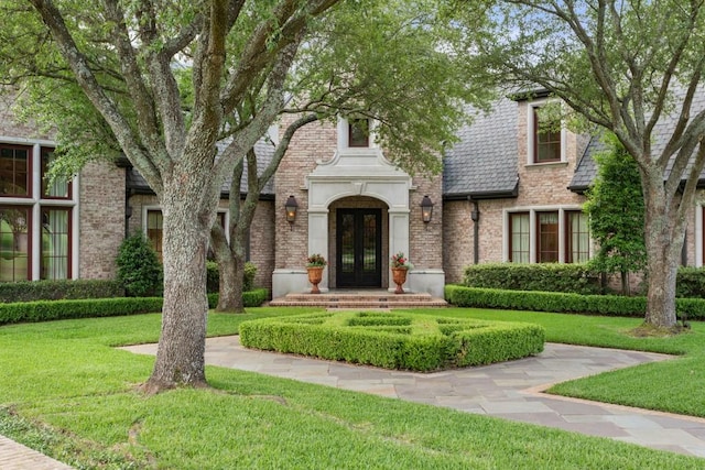 3048 Concord Pl, Tyler, TX 75701 - tudor home featuring french doors, a front lawn, and brick siding
