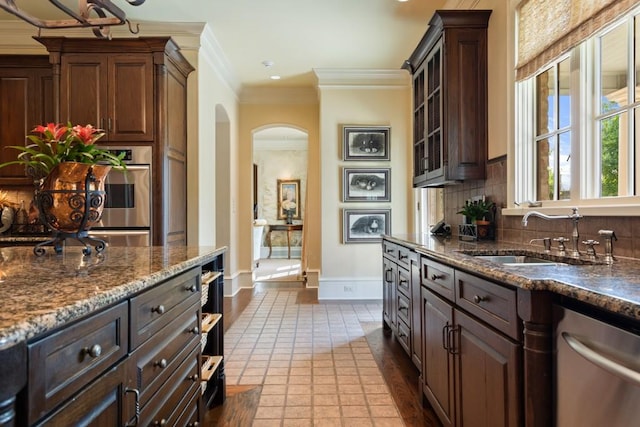 3048 Concord Pl, Tyler, TX 75701 - kitchen with stainless steel dishwasher, arched walkways, ornamental molding, decorative backsplash, and dark stone countertops