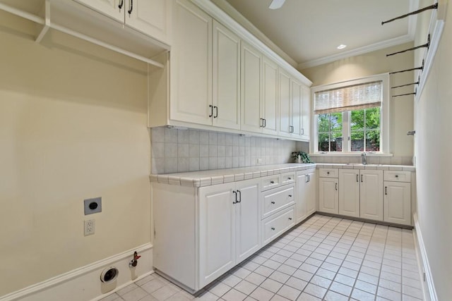 3048 Concord Pl, Tyler, TX 75701 - laundry room featuring hookup for a gas dryer, light tile patterned flooring, electric dryer hookup, cabinet space, and crown molding