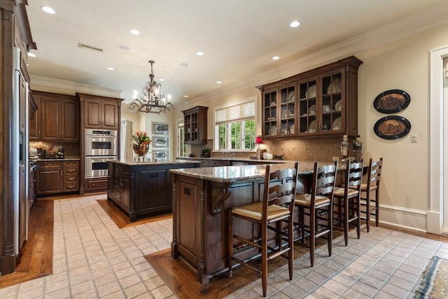 3048 Concord Pl, Tyler, TX 75701 - kitchen featuring double oven, ornamental molding, a peninsula, dark brown cabinets, and a chandelier