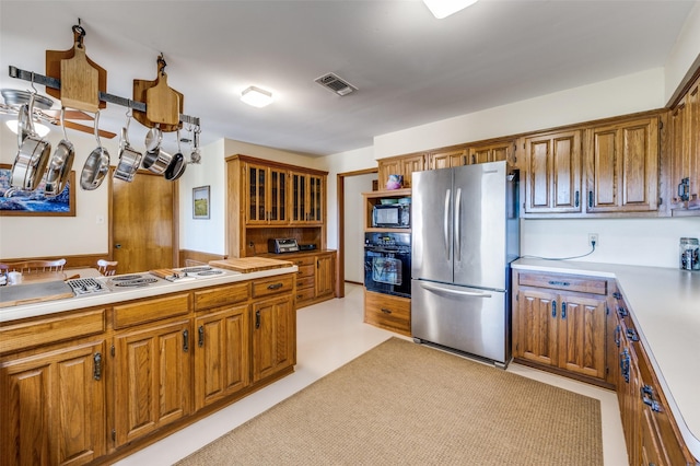 2917 Fladger St, Denton, TX 76207 - kitchen featuring black appliances, light countertops, brown cabinets, and glass insert cabinets