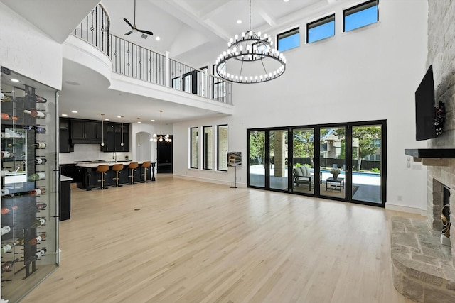 320 W Highland St, Southlake, TX 76092 - living room featuring a towering ceiling, a chandelier, a fireplace, light wood-style floors, and ceiling fan