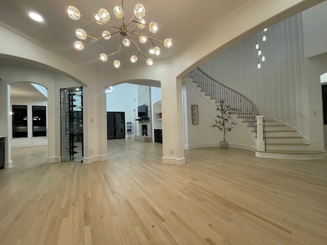 320 W Highland St, Southlake, TX 76092 - unfurnished living room featuring light wood-type flooring, arched walkways, stairs, a chandelier, and a fireplace with raised hearth