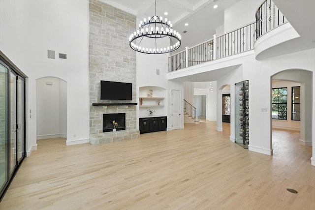 320 W Highland St, Southlake, TX 76092 - unfurnished living room with a towering ceiling, arched walkways, light wood-style floors, a stone fireplace, and stairway