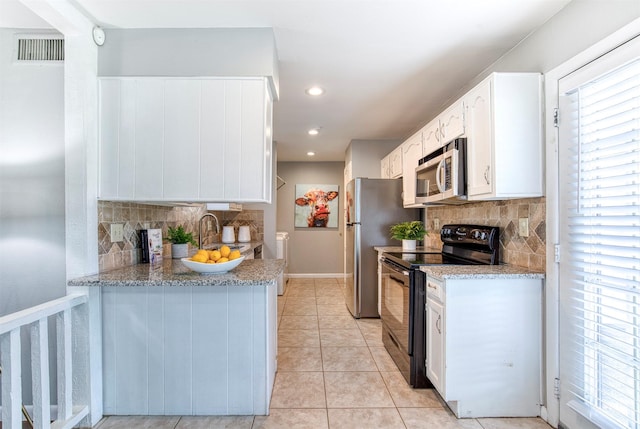 6005 Frontier Ln, Plano, TX 75023 - kitchen with black electric range, stainless steel microwave, backsplash, white cabinetry, and light tile patterned floors