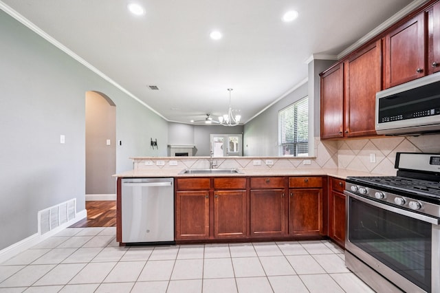 3900 Ironstone Ln, Mckinney, TX 75070 - kitchen featuring stainless steel appliances, a peninsula, ornamental molding, arched walkways, and recessed lighting