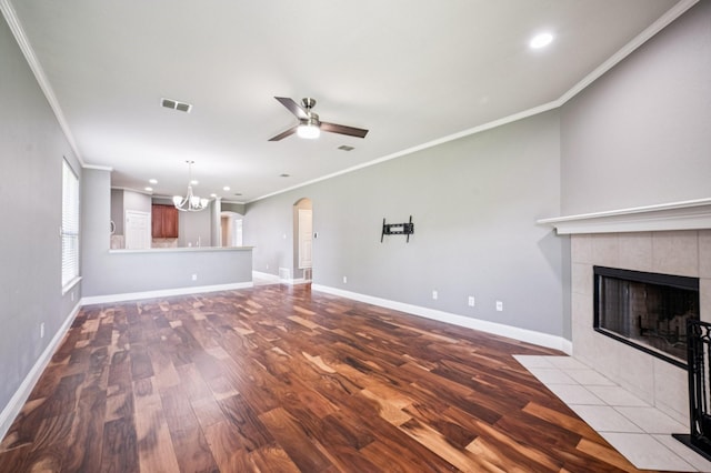 3900 Ironstone Ln, Mckinney, TX 75070 - unfurnished living room with wood finished floors, a ceiling fan, a chandelier, crown molding, and a tile fireplace