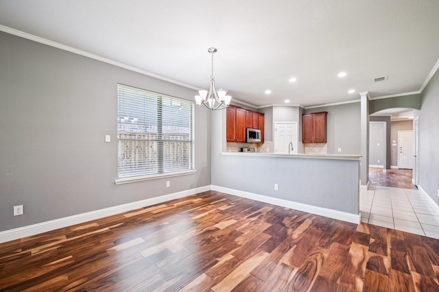 3900 Ironstone Ln, Mckinney, TX 75070 - kitchen with stainless steel microwave, crown molding, wood finished floors, arched walkways, and a chandelier