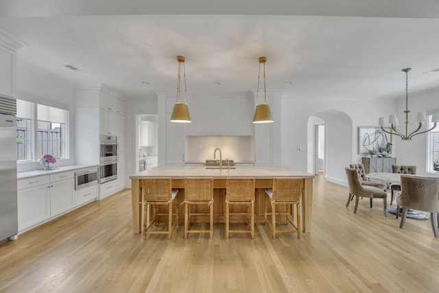 6819 Park Ln, Dallas, TX 75225 - kitchen with stainless steel appliances, light wood-style flooring, a chandelier, white cabinets, and light countertops