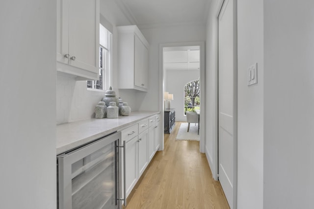 6819 Park Ln, Dallas, TX 75225 - bar with beverage cooler, light wood-type flooring, and decorative backsplash