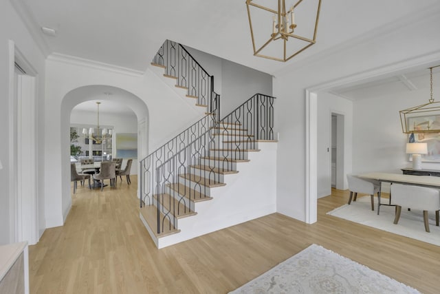 6819 Park Ln, Dallas, TX 75225 - staircase featuring a chandelier, arched walkways, wood finished floors, and ornamental molding