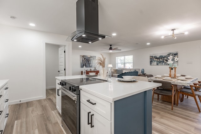 1105 Trellis Dr, Garland, TX 75040 - kitchen with island range hood, stainless steel electric range, light wood-style flooring, white cabinetry, and a ceiling fan