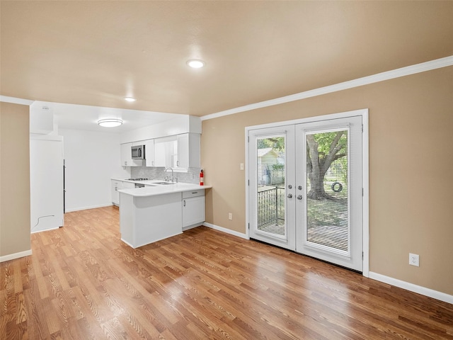 903 20th St, Plano, TX 75074 - kitchen featuring french doors, a peninsula, crown molding, light wood finished floors, and light countertops