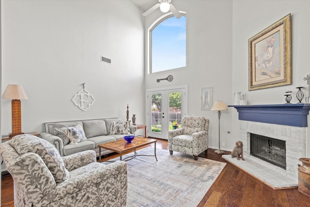 6749 Misty Hollow Dr, Plano, TX 75024 - living room featuring a brick fireplace, a ceiling fan, wood finished floors, and a towering ceiling