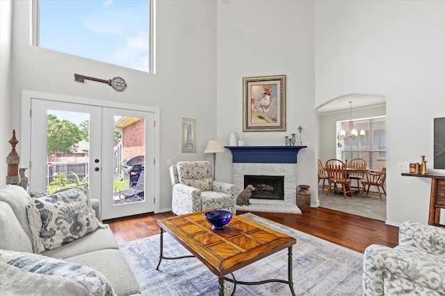 6749 Misty Hollow Dr, Plano, TX 75024 - living room with a high ceiling, wood finished floors, a chandelier, a brick fireplace, and arched walkways