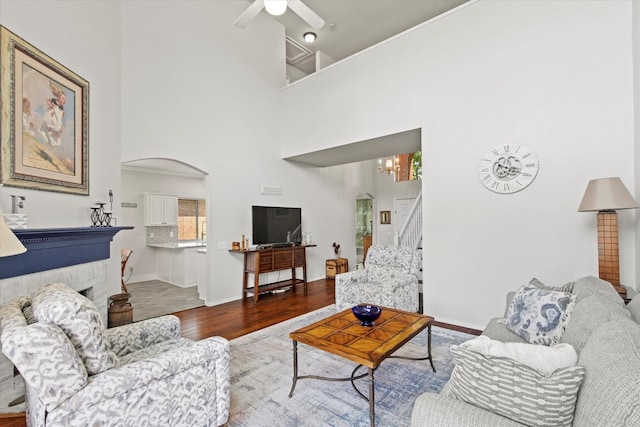 6749 Misty Hollow Dr, Plano, TX 75024 - living room featuring arched walkways, wood finished floors, a towering ceiling, a ceiling fan, and stairway