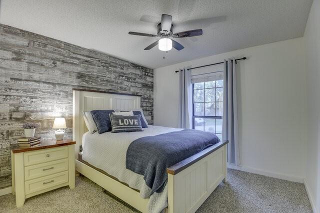 3008 Stone Bluff Ct, Arlington, TX 76017 - bedroom featuring an accent wall, light colored carpet, a textured ceiling, and a ceiling fan