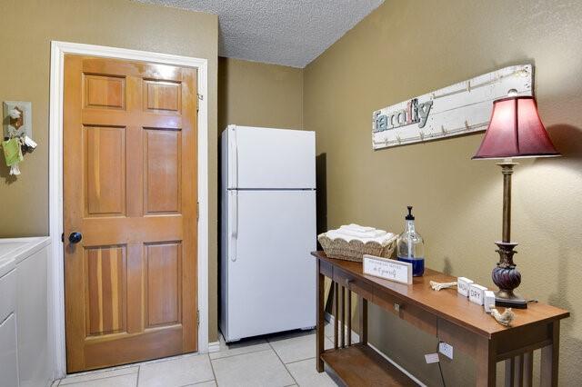 3008 Stone Bluff Ct, Arlington, TX 76017 - kitchen featuring freestanding refrigerator, light tile patterned flooring, and a textured ceiling
