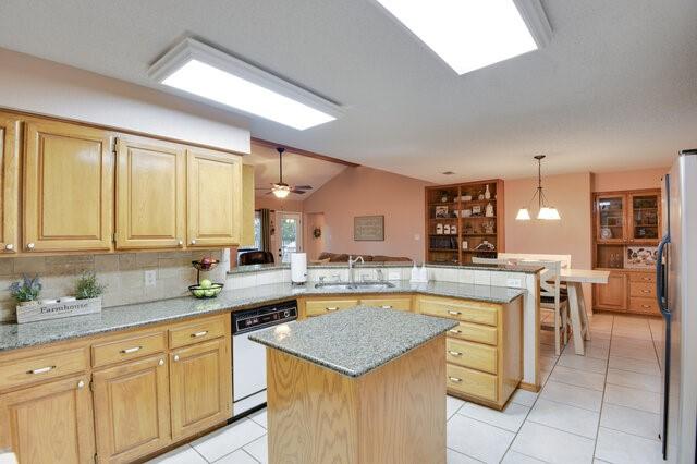 3008 Stone Bluff Ct, Arlington, TX 76017 - kitchen with dishwasher, freestanding refrigerator, a peninsula, light tile patterned flooring, and light stone countertops