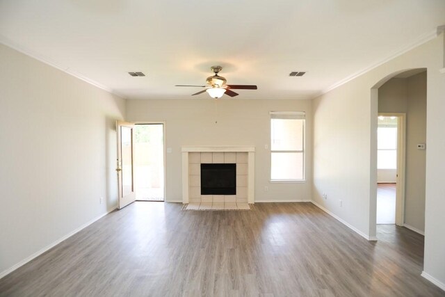 10606 Greenbriar Ln, Rowlett, TX 75089 - unfurnished living room featuring ceiling fan, arched walkways, a tiled fireplace, wood finished floors, and ornamental molding