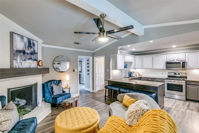 205 N Weatherred Dr, Richardson, TX 75080 - living area with light wood finished floors, a ceiling fan, a fireplace with raised hearth, ornamental molding, and recessed lighting