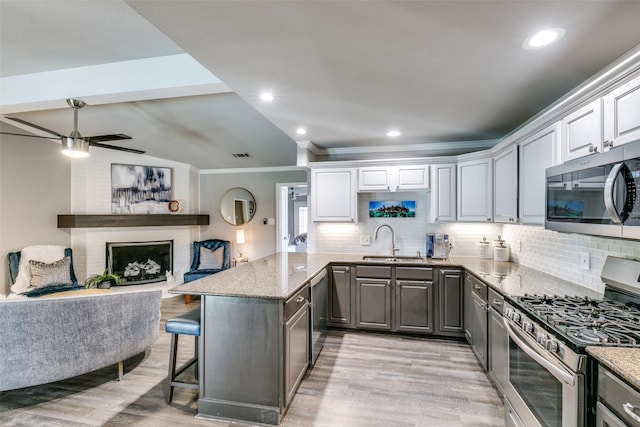 205 N Weatherred Dr, Richardson, TX 75080 - kitchen featuring stainless steel appliances, light wood finished floors, gray cabinets, a kitchen breakfast bar, and crown molding