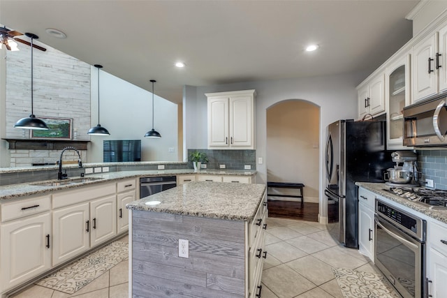 824 Mist Flower Dr, Little Elm, TX 75068 - kitchen with appliances with stainless steel finishes, arched walkways, tasteful backsplash, light tile patterned floors, and recessed lighting