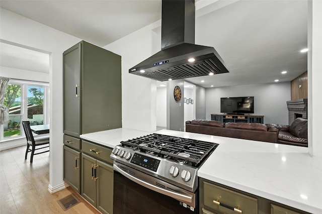 336 Davis Dr, Desoto, TX 75115 - kitchen featuring wall chimney exhaust hood, stainless steel range with gas cooktop, light wood-style flooring, light stone counters, and open floor plan
