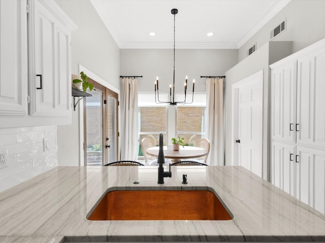 3813 Fall Wheat Dr, Plano, TX 75075 - kitchen with a chandelier, light stone countertops, tasteful backsplash, white cabinets, and crown molding