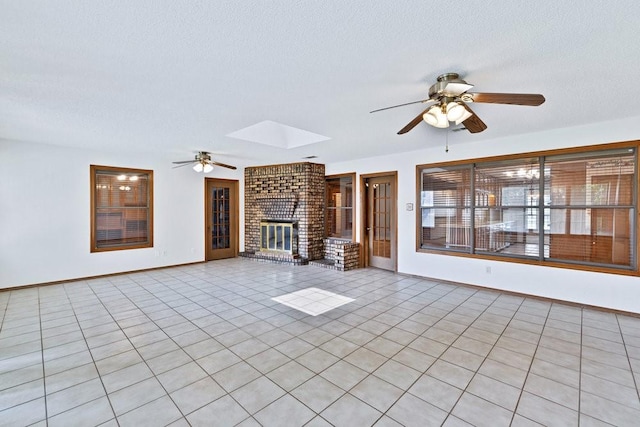 7254 Hialeah Cir W, North Richland Hills, TX 76182 - unfurnished living room featuring a ceiling fan, a fireplace, a textured ceiling, a skylight, and light tile patterned floors