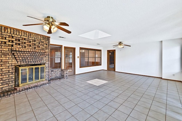 7254 Hialeah Cir W, North Richland Hills, TX 76182 - unfurnished living room with a ceiling fan, a textured ceiling, a skylight, a fireplace, and tile patterned floors