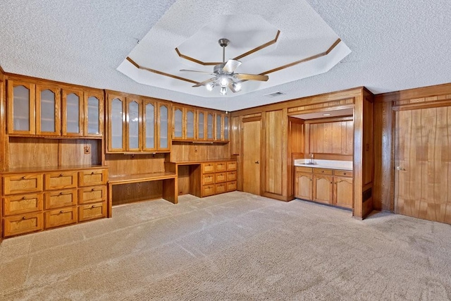 7254 Hialeah Cir W, North Richland Hills, TX 76182 - unfurnished bedroom with built in desk, a textured ceiling, carpet, wood walls, and a raised ceiling