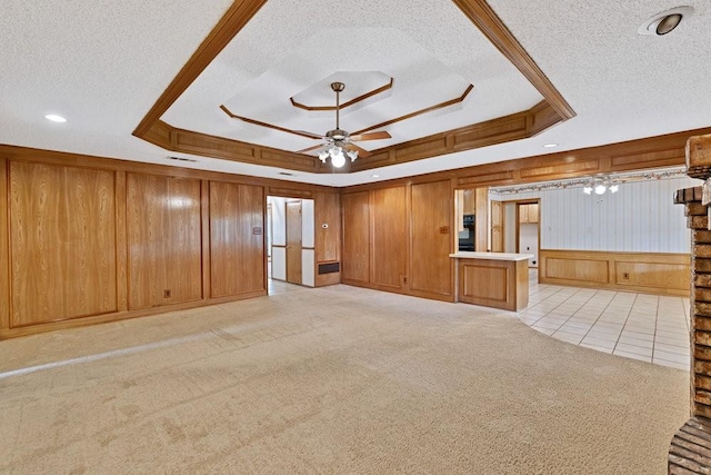 7254 Hialeah Cir W, North Richland Hills, TX 76182 - unfurnished living room featuring a tray ceiling, a textured ceiling, ceiling fan, wood walls, and light colored carpet