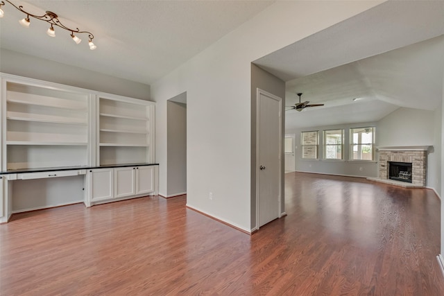 122 Ashbrook Trl, Forney, TX 75126 - unfurnished living room featuring wood finished floors, a ceiling fan, a fireplace with raised hearth, and vaulted ceiling