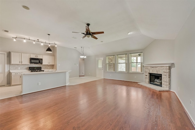 122 Ashbrook Trl, Forney, TX 75126 - unfurnished living room featuring ceiling fan, a brick fireplace, light wood-type flooring, a chandelier, and vaulted ceiling